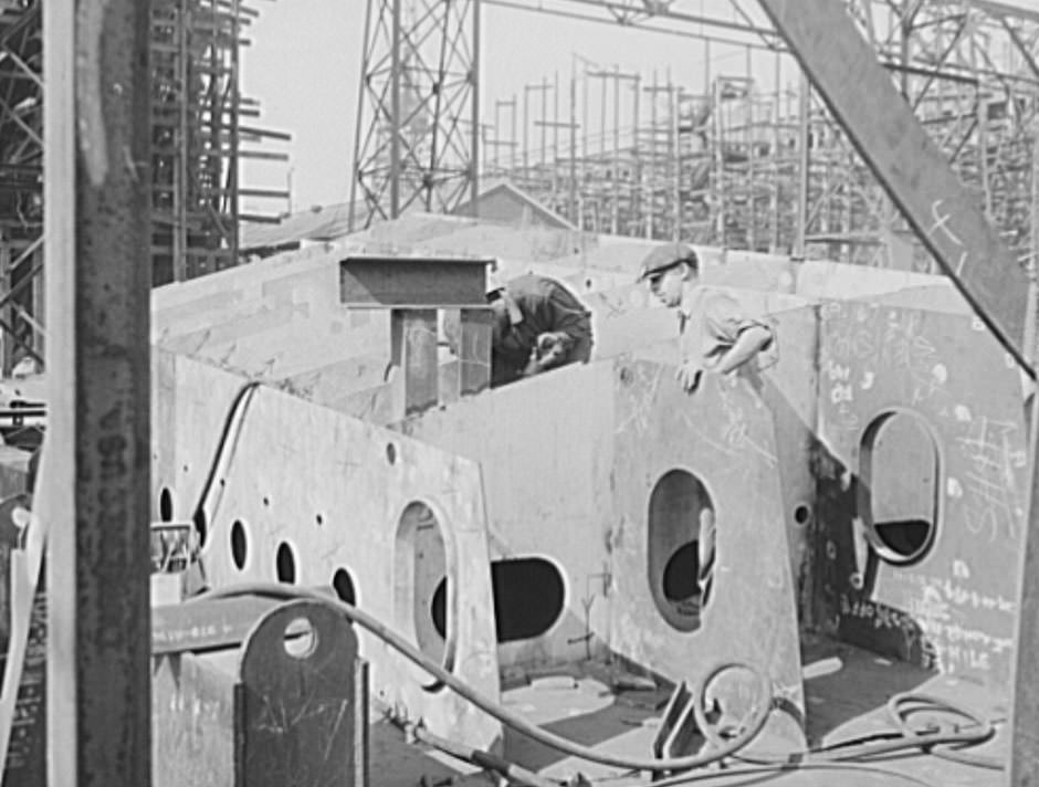 #21 These two workers are assembling the hull section of a new cruiser. Four new navy cruisers are on the ways here, and a huge battleship, 1941