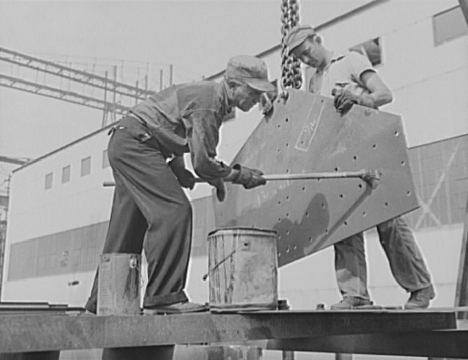 #37 These workers are red-leading a plate, to prevent corrosion. Only the highest quality materials will serve for the new warcraft under construction for Uncle Sam’s two-ocean fleet, 1941