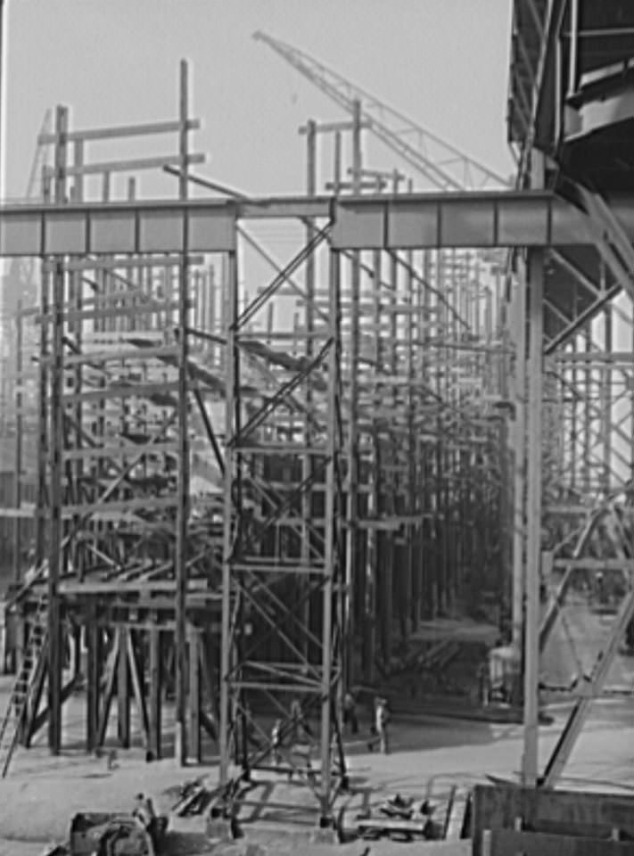 #44 Behind all the scaffolding a new cruiser is beginning to take shape, one of four under construction on the Newport News ways, 1941