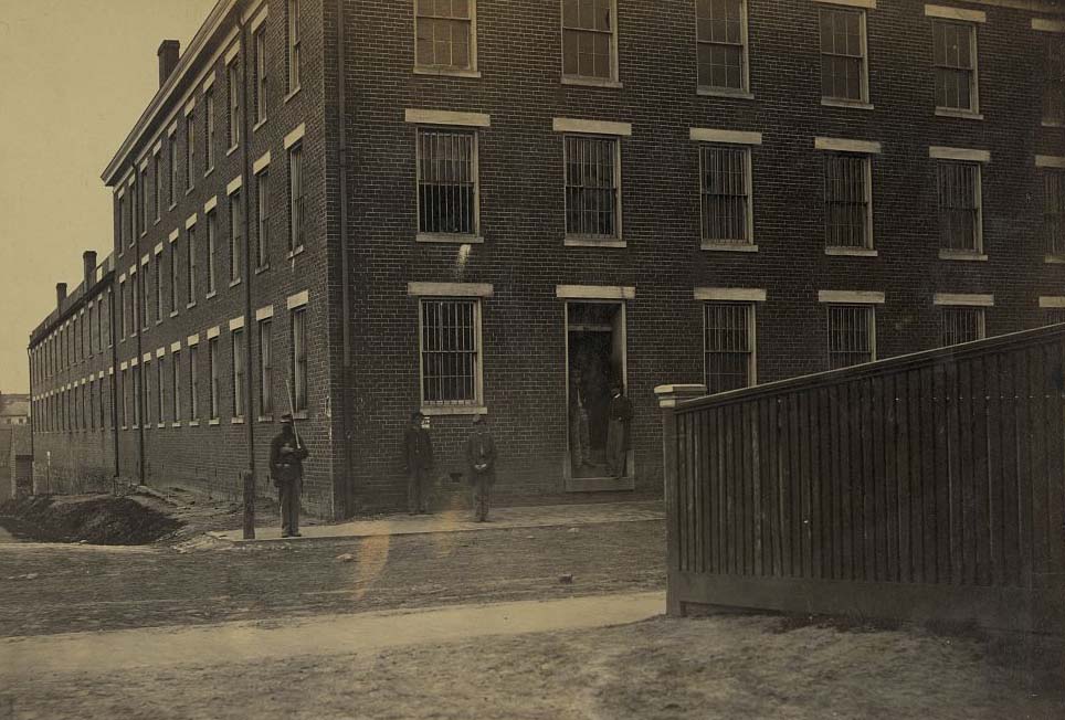 #140 A Union guard standing next to Castle Thunder, a Confederate military prison in Richmond, Virginia, 1865