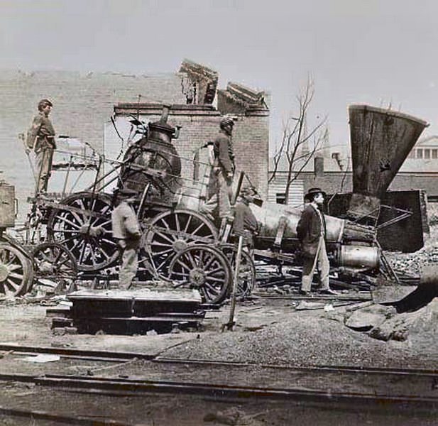 #113 Union soldiers and a civilian standing on and near a locomotive at the Richmond and Petersburg Railroad Depot which was destroyed by Confederate troops as they fled the city, 1865