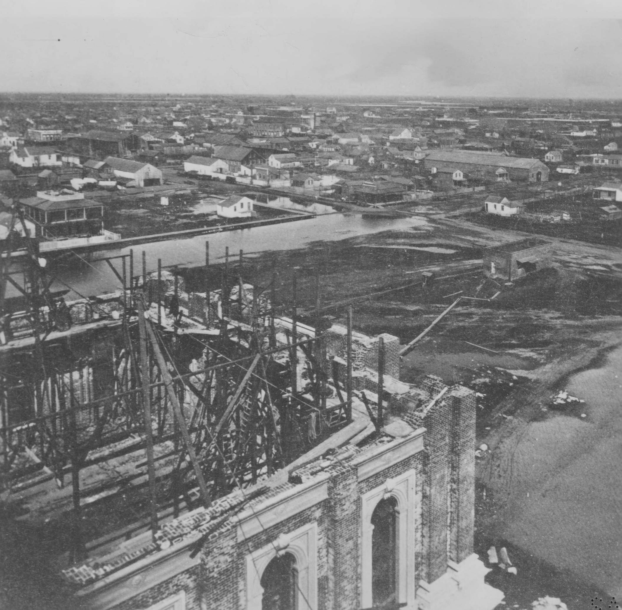 #96 A rainy day in 1868 is viewed from on high upon the unfinished dome of the California State Capitol building. N Street and 12th Street intersect in the upper portion of the photograph.