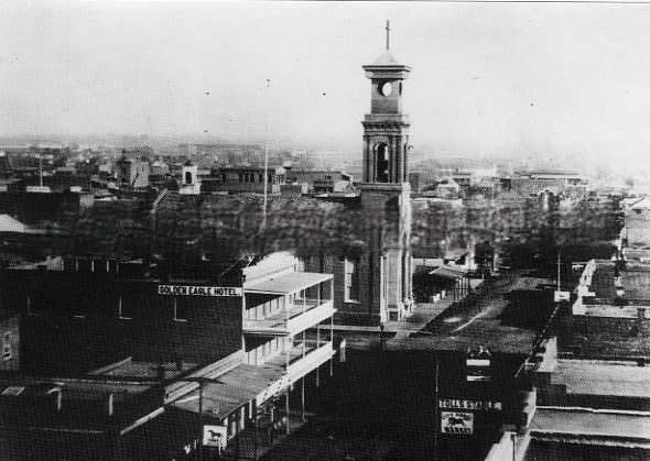 #118 Street scenes of businesses on K Street from 7th Street looking east in 1869. The Golden Eagle Hotel is on the left and St. Rose of Lima Church is across 7th Street further on the left.
