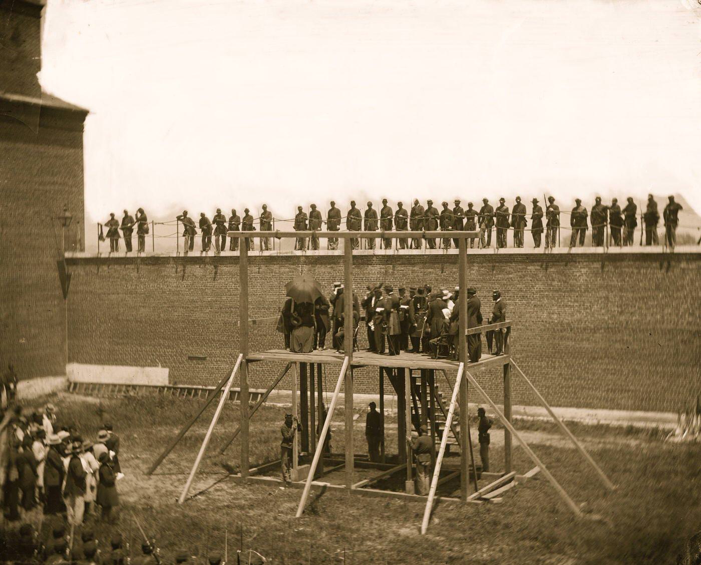 #106 The four condemned conspirators (Mrs. Surratt, Payne, Herold, Atzerodt), with officers and others on the scaffold; guards on the wall, Washington, D.C., 1865