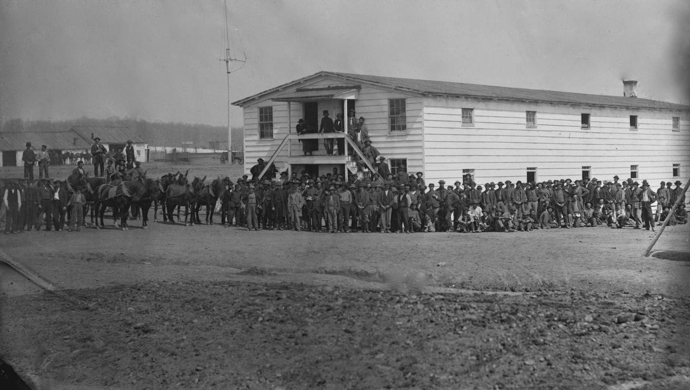 #177 Exterior view of the mess house at the government stables, with a large group of men gathered around, Washington, D.C., 1865