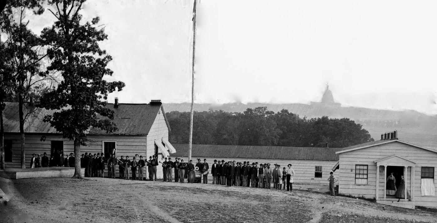 #179 A military band standing before the officers’ quarters at Harewood Hospital, located on the farm of WW Corcoran, at 7th Street Road near the Soldiers’ Home, 1864.