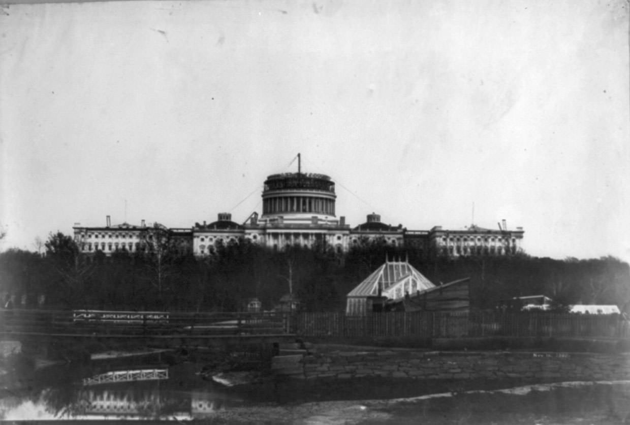 #27 Construction of the new Capitol Dome in 1860. The former Botanic Garden Conservatory, originally located on the National Mall, is in the foreground.