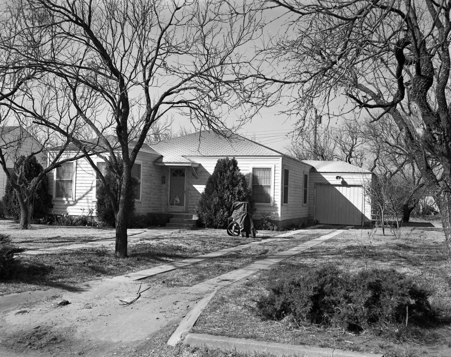 #84 An exterior view of a wooden house with a garage, 1958