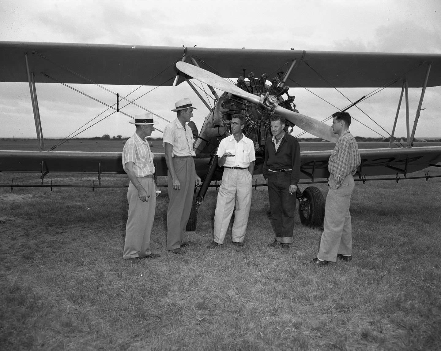 #117 Five men standing in front of prop plane, 1954