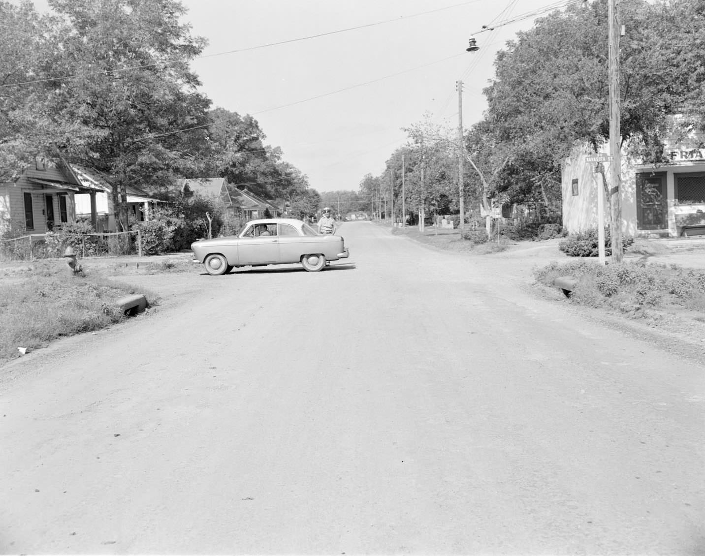 #192 A car parked in the middle of the intersection of Navasota and Holly, 1954