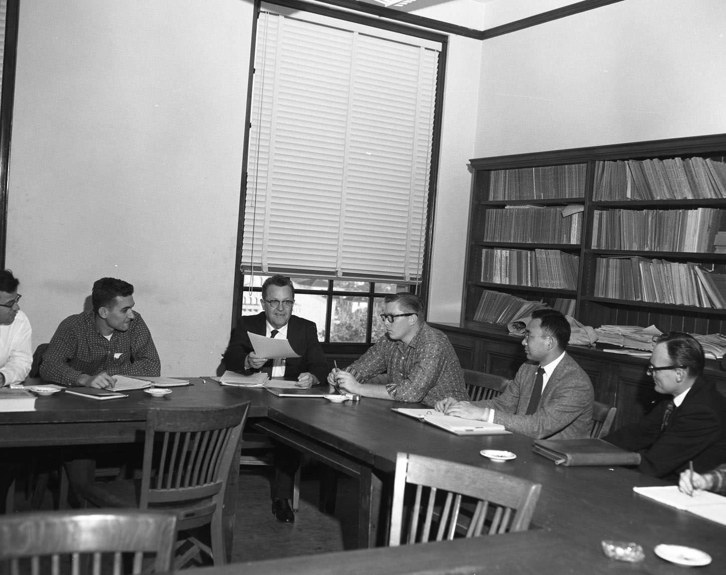 #70 Men in discussion at table, probably administrators, 1958