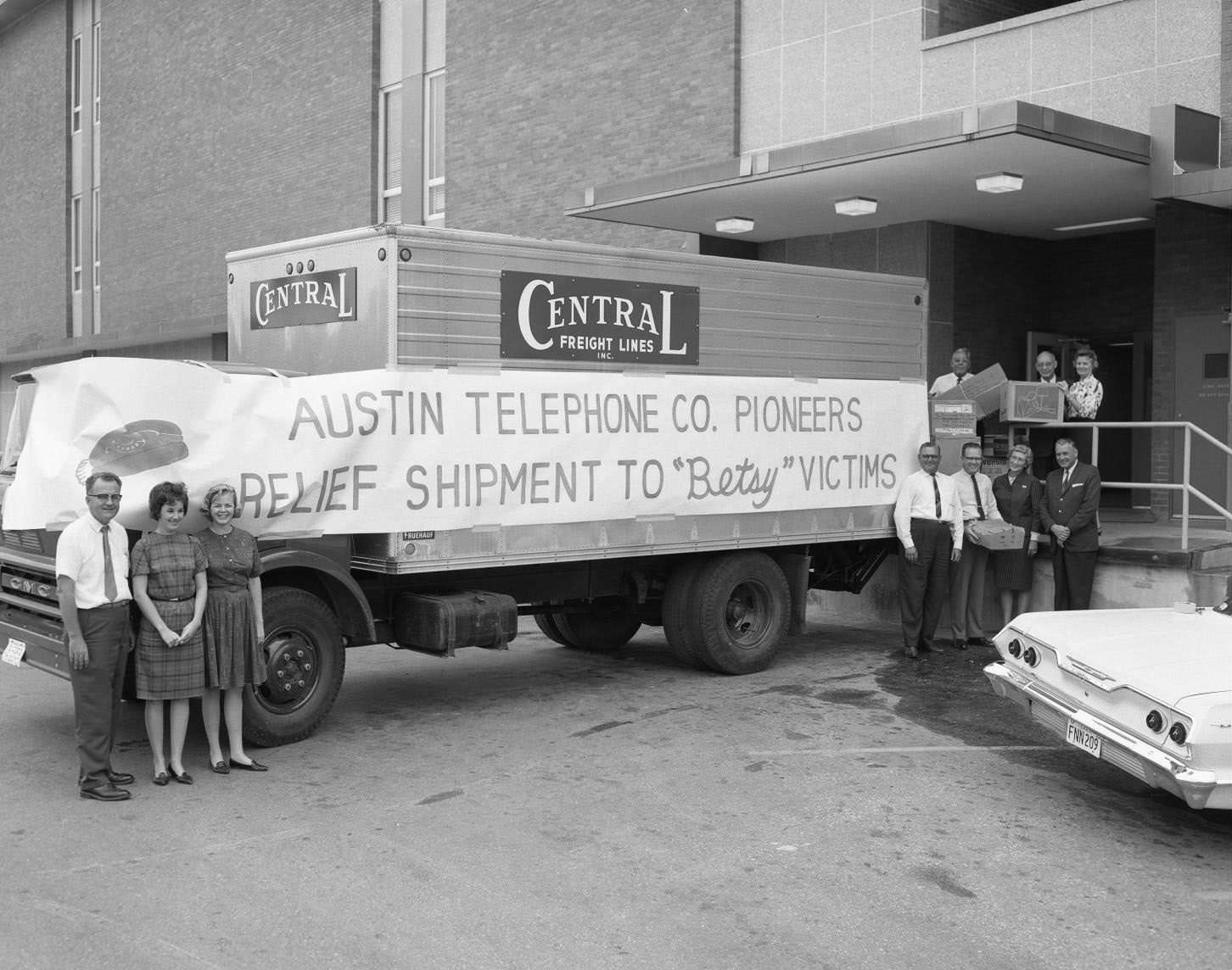 #145 Austin Telephone Co. Pioneers stand outside relief truck, seeing off goods to the victims of Hurricane Betsy in New Orleans, 1965