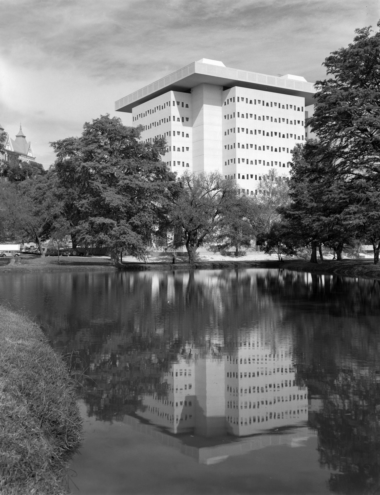 #35 A pond surrounded by trees near a tall, postwar building, 1969