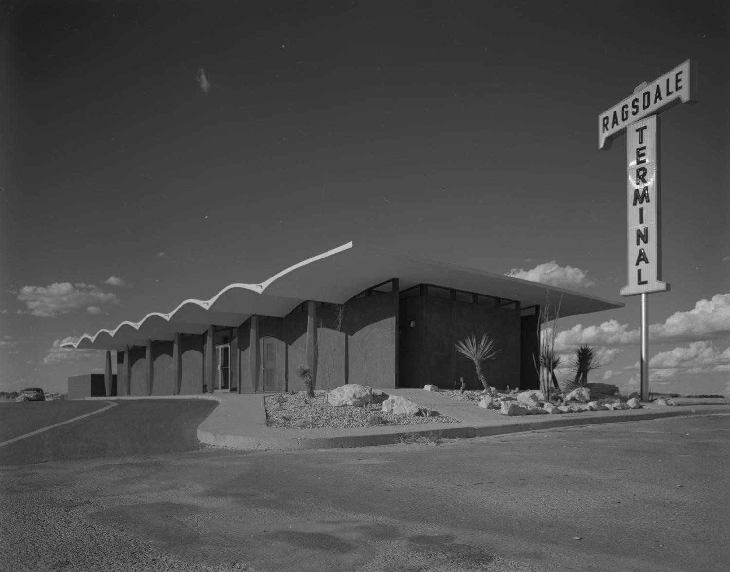 #183 Ragsdale Terminal with an exterior facade that is dark with matching dark columns that can be seen on the left wall, along with a glass door entrance, 1962