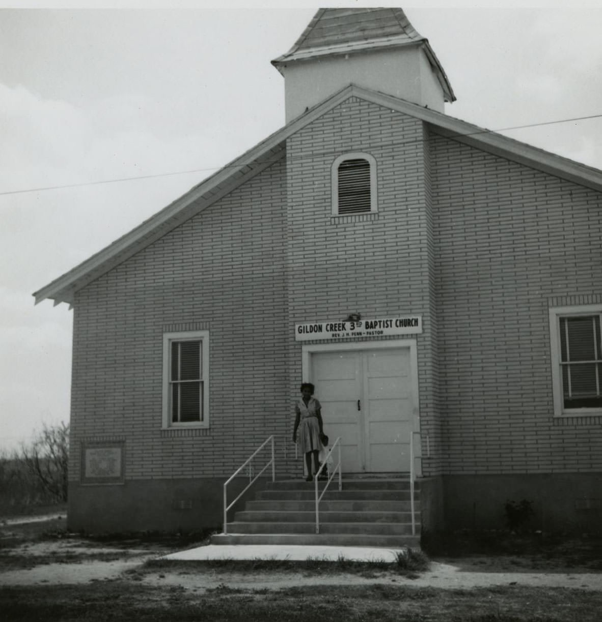 #206 A woman standing on the front steps of the Gildon Creek Third Baptist Church building, 1962