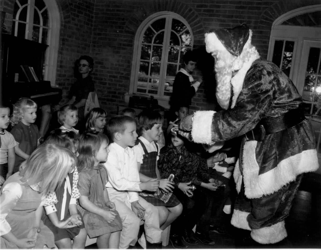 #101 A Tiny Tot Christmas Party at Hancock Recreation Center. Santa Claus hands out candy canes to a group of children, 1966