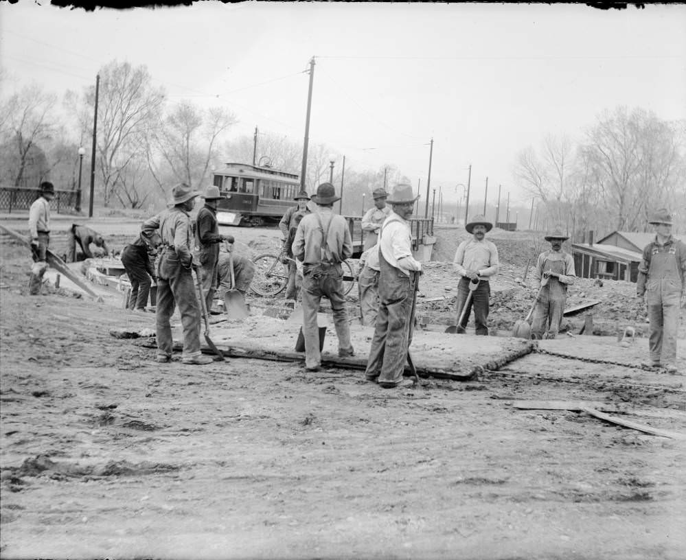 #140 Workmen pour concrete into forms for a gutter near the Alameda Avenue bridge in Denver, 1909