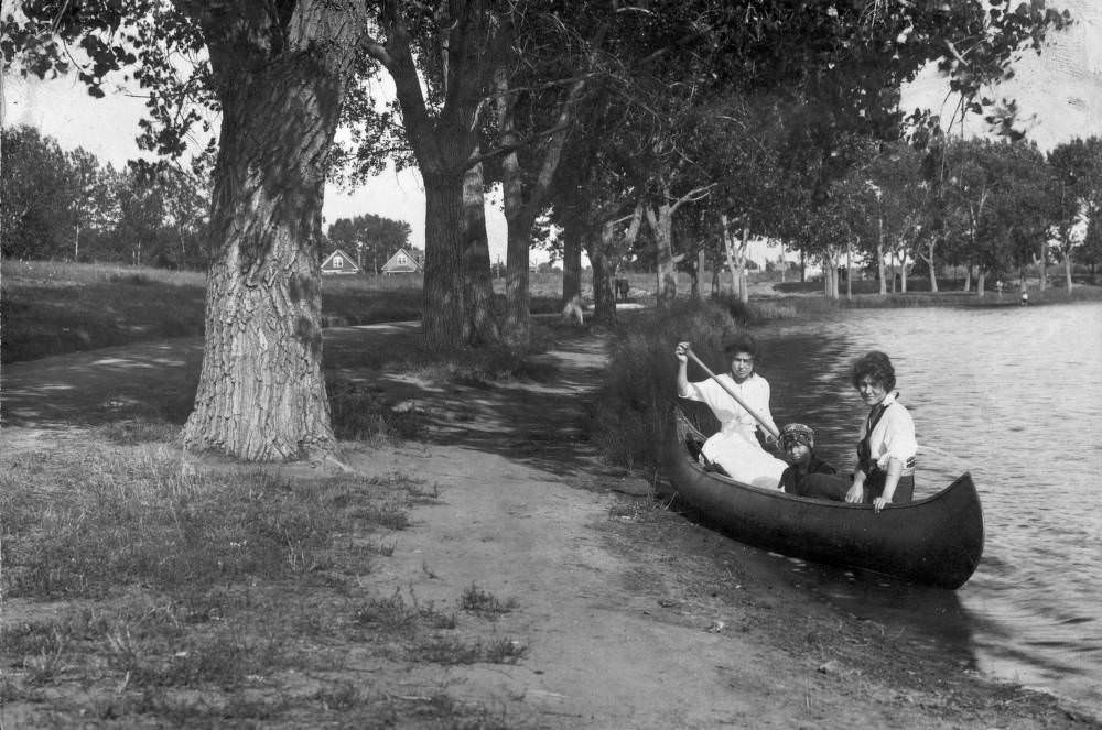 #35 Two women and a young girl sit in a canoe near the shore of Smith Lake in Washington Park, Denver, 1909