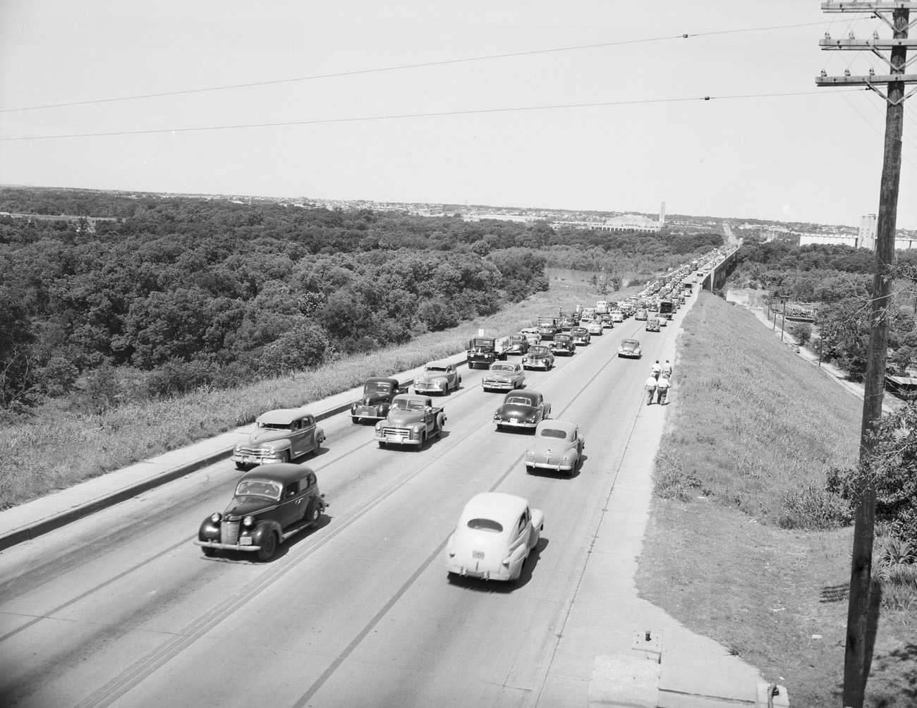 #121 Flood Damage–Center of North Bridge. Automobiles are on the road and people are walking at the side of the street, 1949