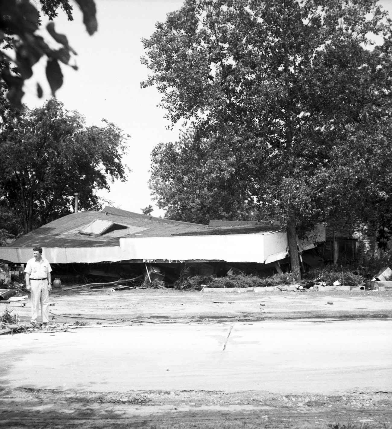 #122 Man standing in front of remains of damaged house, 1949