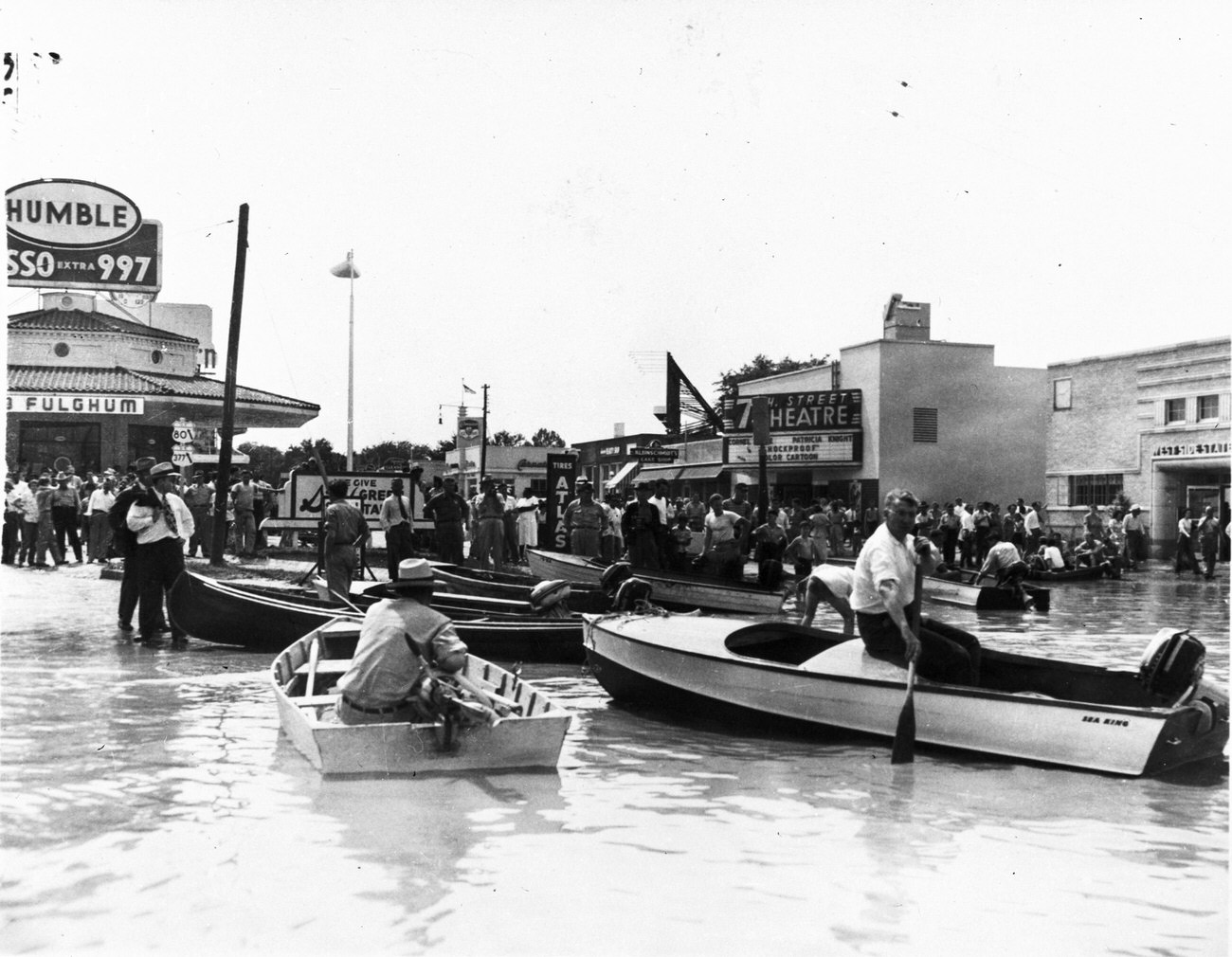 #24 Flood at Fort Worth intersection of University and 7th Street near 7th Street Theater with people in boats, May 1949