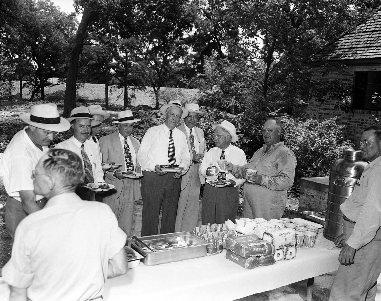 #92 Citizens Flood Control Committee men, along with city and county officials. Amon Carter Sr. and group gathered around a picnic table.