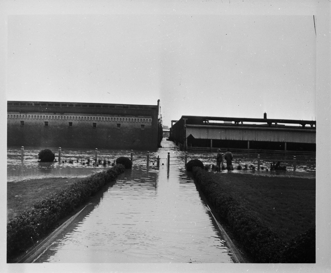 #96 The Fort Worth Stockyards after a flood. Two men are standing by a fence looking at the damage.