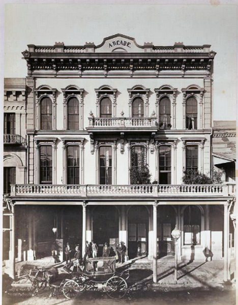 #42 View of the three-story Arcade Hotel with balcony across the second floor, partial balcony at third floor, 1875