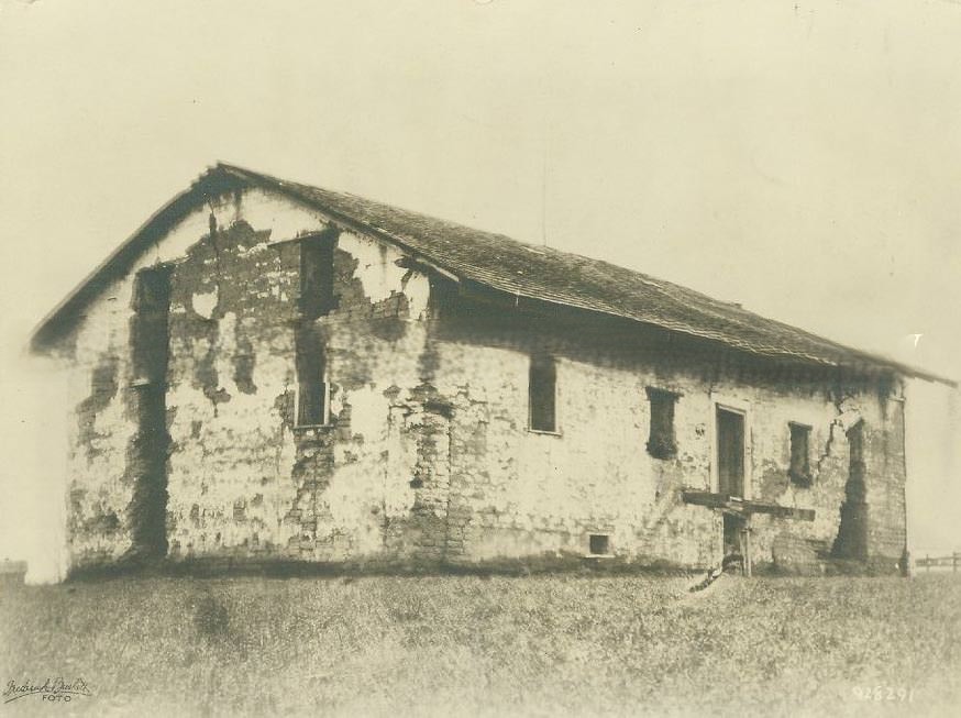 #57 Six men and two dogs pose in front of this small wooden store, 1878