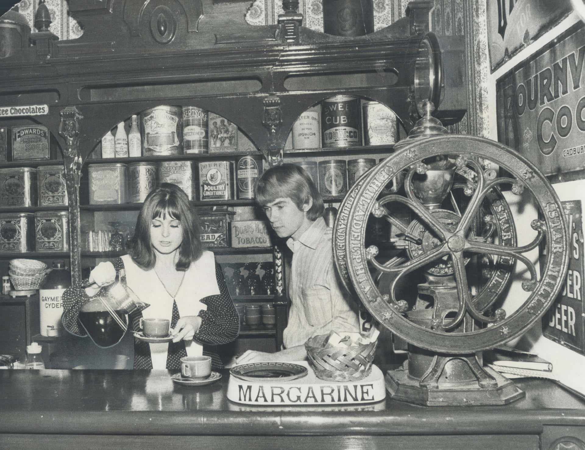 #115 Surrounded with antiques; Joy and Neil Dixon preside at the counter of their coffee house; Grumbles; at 71 Jarvis St., 1970