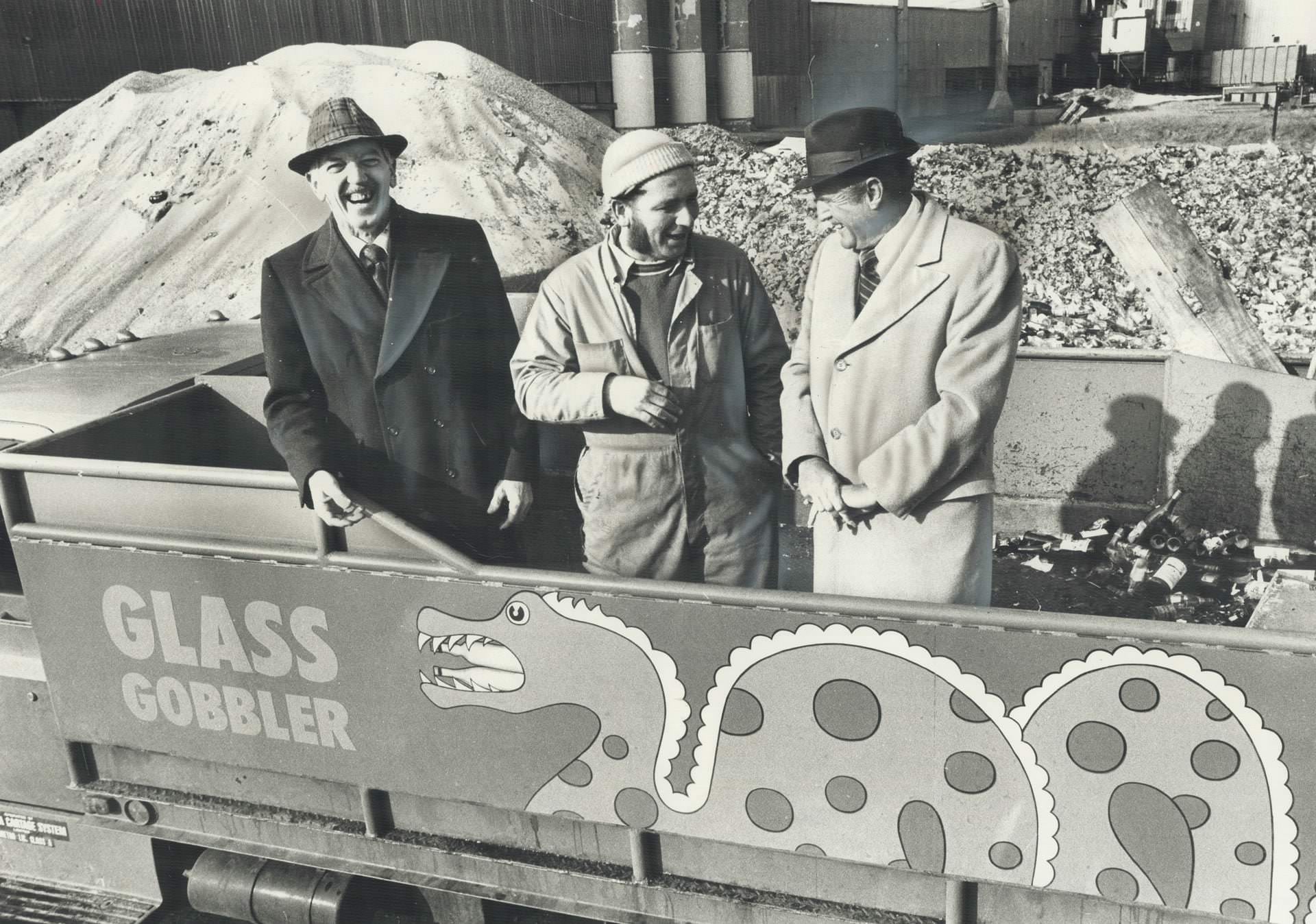 #116 Early recycling – Three men in the truck are pointing to the name on the side; Glass Gobbler; which defines its job, 1977