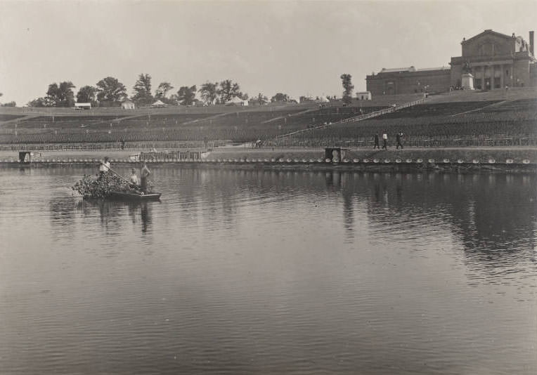 #108 Three men in a row boat clear debris from the Grand Basin, Forest Park, in preparation for performances of the Pageant and Masque of St. Louis, 1914
