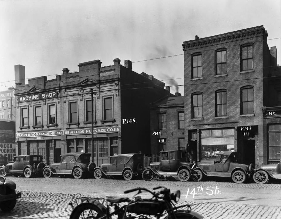 #63 View of the buildings whose addresses were 111, 113, 115, 119 14th Street and cars parked in front, 1925