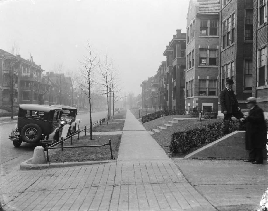 #90 The view north down Blair Ave. from just north of O’Fallon Street, 1925. The building on the left is 1311 Blair Ave. Two men stand at a driveway on the right.