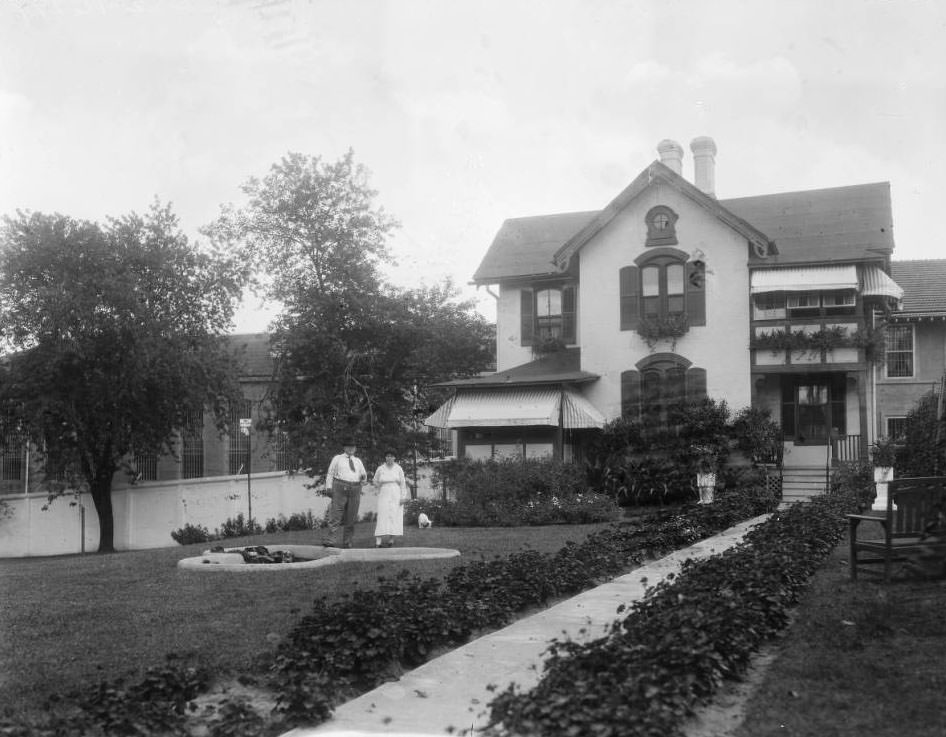 #91 View of a man, woman (and dog) posing on the grounds at the Superintendent’s residence of the St. Louis City Workhouse at the SE corner of South Broadway & Meramec Street.