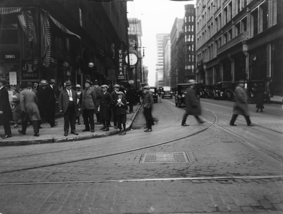 #96 View of looking east on Locust at 7th of several men and boys standing on the corner in front of Judge & Dolph’s Drugstore, 1925
