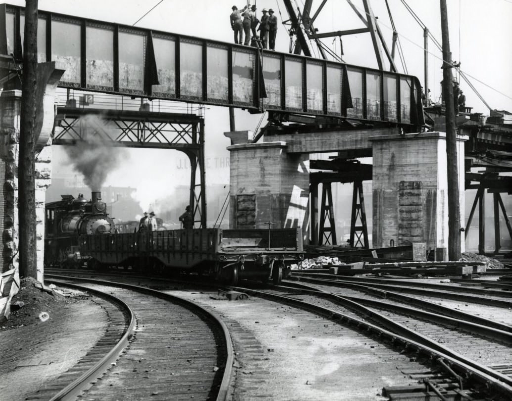 #16 Men setting a girder for elevated railway. Below, a locomotive is in the process of switching cars, 1910