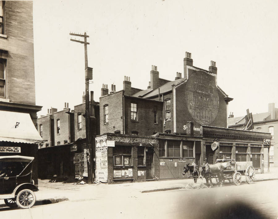 #56 A team of horses taking a break in front of a row of buildings on 20th Street, 1915