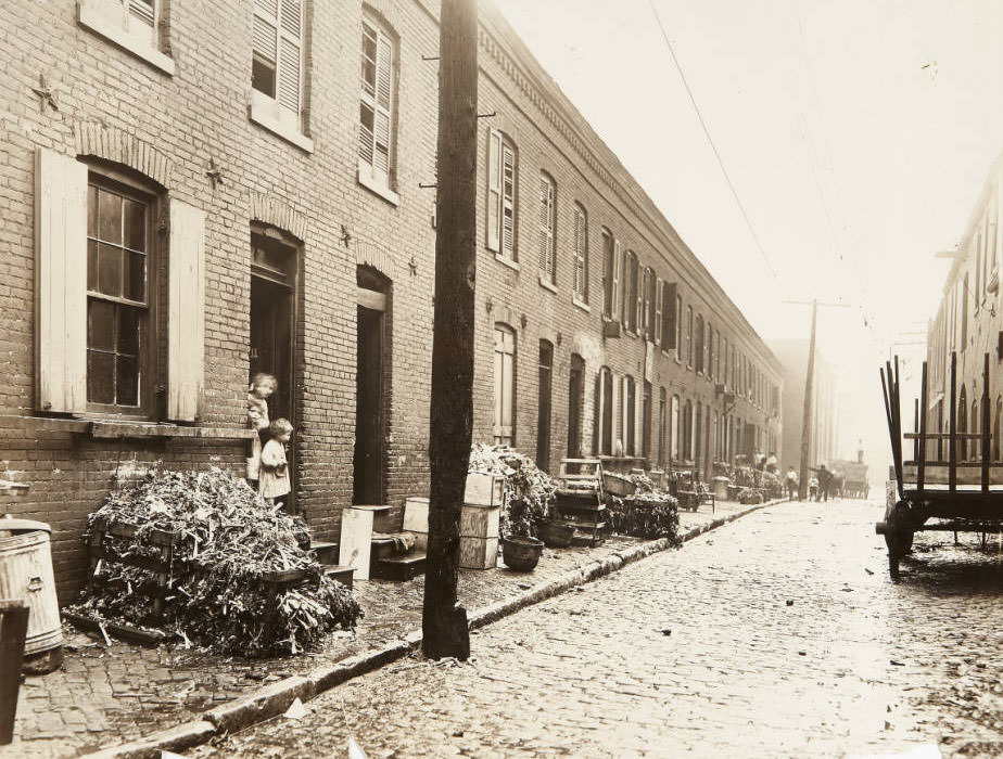 #82 A long rowhouse along an unidentified cobblestone street, 1915