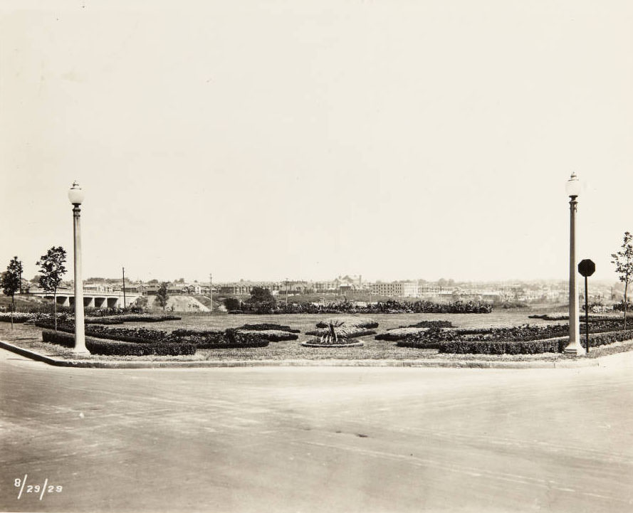 #90 A well-maintained greenspace with trimmed hedges and flower beds at an unidentified intersection, 1910s