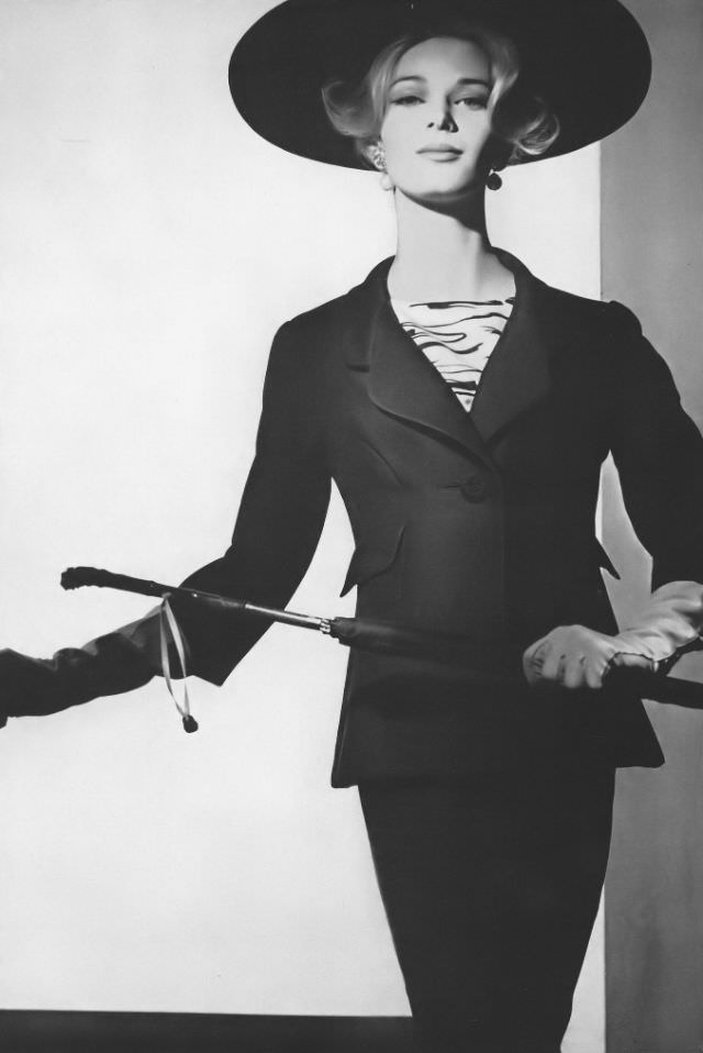 #8 Anne de Zogheb in black silk worsted suit with a long flaring jacket worn with a black and white zebra-striped silk blouse, by Adele Simpson, hat by Mr. Arnold, January 1, 1962