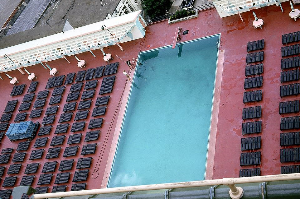#56 Hotel workers are up early to clean a swimming pool before all the guests descend to swim and lie on the sun loungers