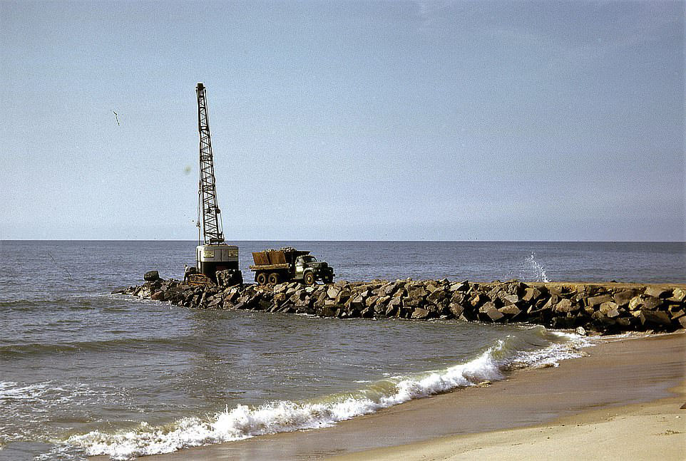 #60 A truck drives away from a small crane that had been placed at the end of a shore defence