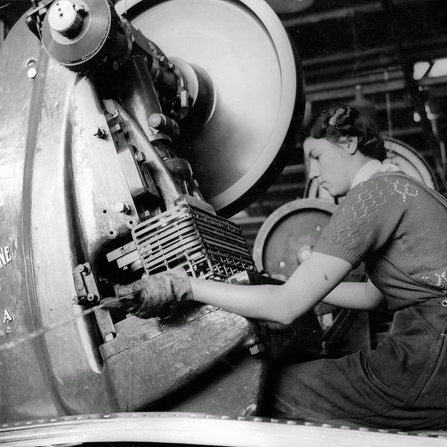 #20 A young woman working at a small press making ammunition boxes.