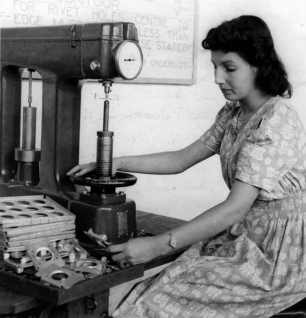 #7 A young woman testing parts for hardness at a munitions factory in South Australia.