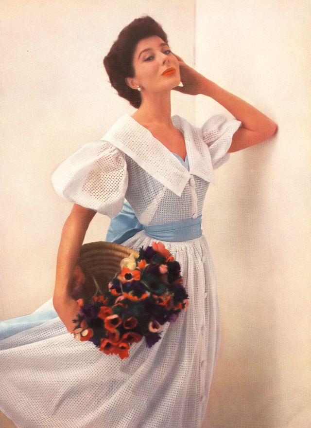 #104 Bettina in dress with two lives; by day broderie Anglaise over sky-blue taffeta; at night the overdress is removed to reveal the lining as a short décolleté evening dress by Susan Small, 1952