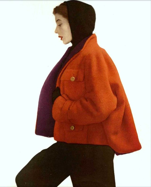 #68 Bettina in brick-red wool jacket lined in purple, worn over black hooded sweater and black gabardine pants, by Manguin, 1950