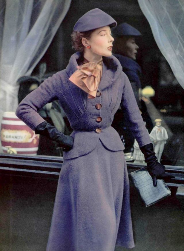 #84 Bettina in violet wool suit, jacket is fitted with boldy notched lapel, skirt is bell shaped, blouse in tortoise shell silk by Paquin, 1951