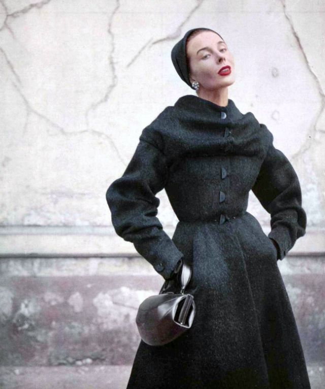 #91 Bettina in furry wool redingote with cape-like shawl clasped over shoulders, fastened with whimsical half buttons, by Jean Dessès, 1952