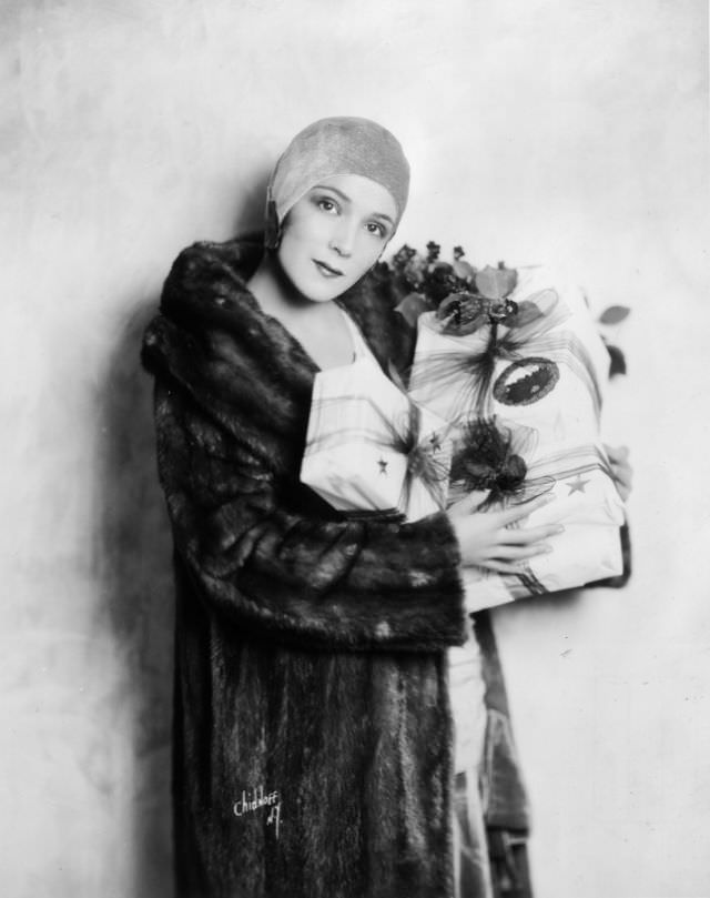 #81 Dolores Del Río wears a mink fur coat and carries Christmas presents, 1925.